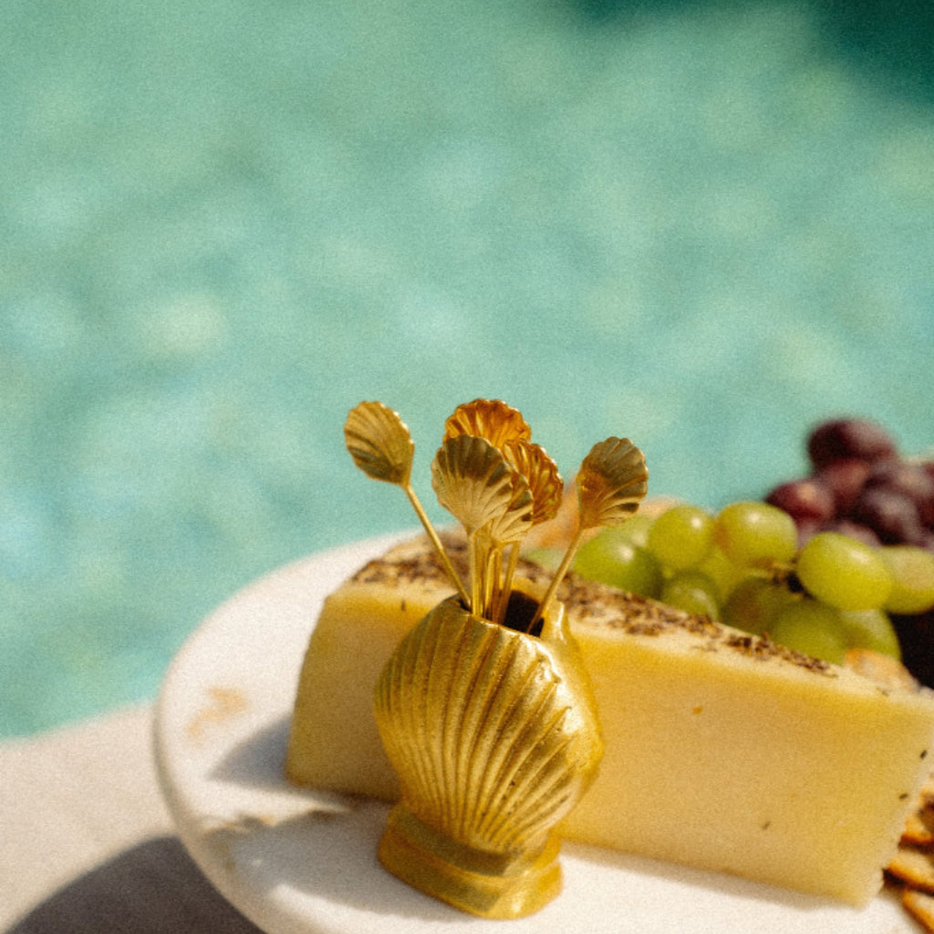 Platter of cheese, grapes, and crackers by a poolside