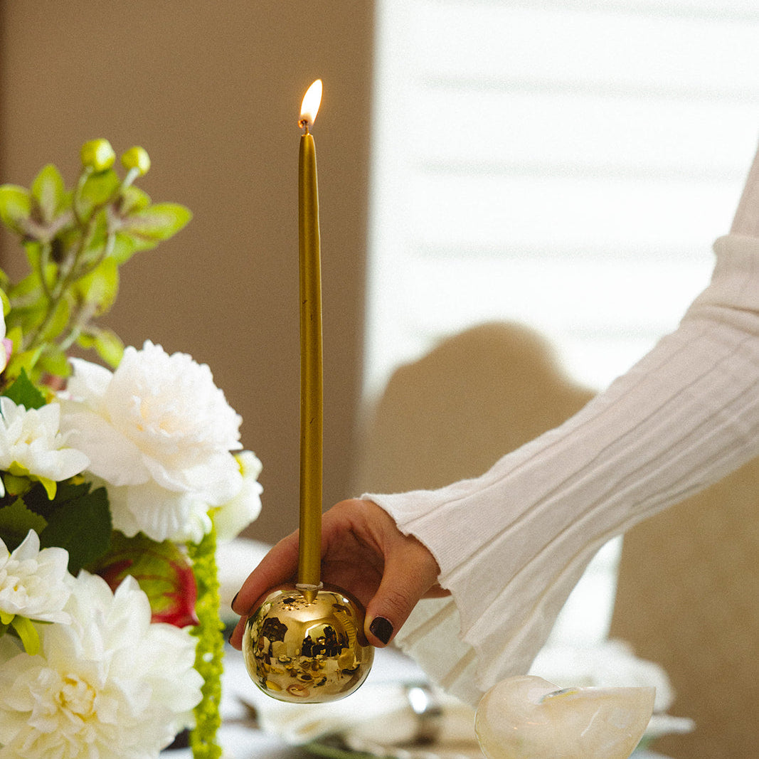 Decorative candle holder on a table with flowers and other items