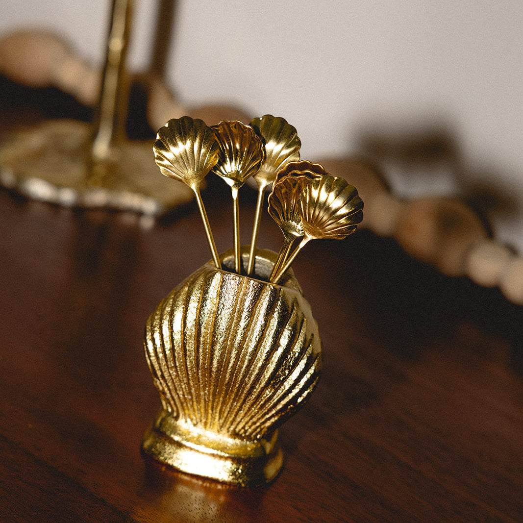Gold decorative vase with shell design on a wooden surface