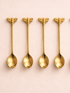 Four gold bee-shaped spoons on a pink background