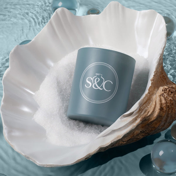 Blue candle with 'S&C' logo in a shell on water