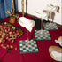 Decorative table setting with checkered coasters, grapes, and decorative items on a red tablecloth.